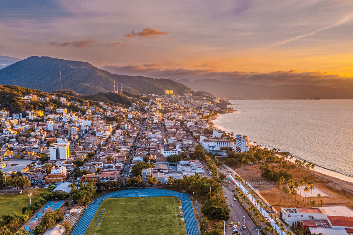 Vista aérea de Puerto Vallarta al atardecer, con la costa, la sierra y el malecón